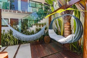 an outdoor patio with two hammocks and a tree at Pousada Praiana in Porto De Galinhas