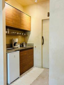 a kitchen with a white refrigerator and wooden cabinets at Apartamento Morro de São Paulo Centro - Mirar in Morro de São Paulo