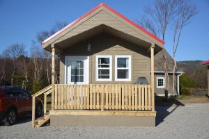 ein kleines Haus mit Zaun auf einem Parkplatz in der Unterkunft Gros Morne Tiny Chalets in Rocky Harbour