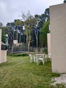 einen Tisch und Stühle in einem Garten mit Bäumen in der Unterkunft Quetrihue Mar de las Pampas in Mar de las Pampas