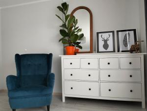 a bedroom with a dresser and a blue chair and a mirror at Przystań in MaryLin