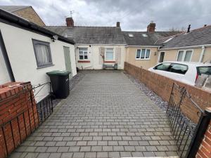 a driveway of a house with a fence and a car at Miners cottage DH1 Bungalow Free Parking Longstay in Sheepscar