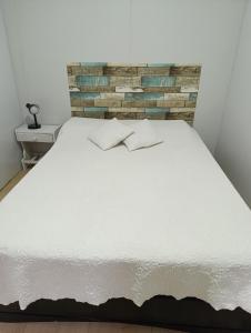 a white bed in a room with a brick wall at Casa en Las Toscas in Las Toscas