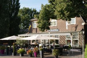 a restaurant with tables and umbrellas in front of a building at De Gouden Molen in Rossum