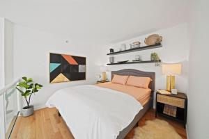 a bedroom with a bed with white sheets and orange pillows at The Urban Lofts in Vancouver