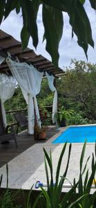 a white pergola next to a swimming pool at Chalé do João e do Chico Garfield in Jaboticatubas