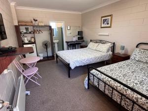 a bedroom with two beds and a table and a kitchen at ALPINE COUNTRY MOTEL 4mile in Cooma