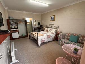 a bedroom with a bed and a couch at ALPINE COUNTRY MOTEL 4mile in Cooma