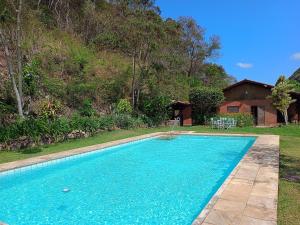 a swimming pool with blue water in a yard at Aurora Homestead in Araras Petropolis