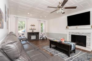 a living room with a couch and a flat screen tv at Kernersville King Beds Hot Tub Arcade Firepit in Kernersville