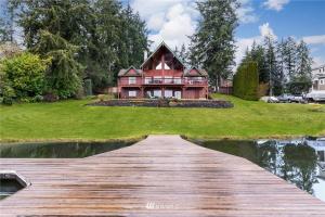 a wooden walkway leading to a house on a lake at Beautiful Private Lake Lodge with Private Dock and Mountain Views in Spanaway