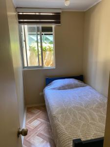 a small bedroom with a bed and a window at Departamento sector Villa Dulce Viña del Mar in Viña del Mar