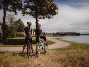 Boussu-lez-WalcourtにあるFamily Villa by the Lakeの湖の横の道で自転車に乗る男女