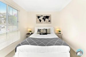 a white bedroom with a bed and two tables at Aircabin - Oxley Park - Lovely & Comfy - 2 Beds in Colyton
