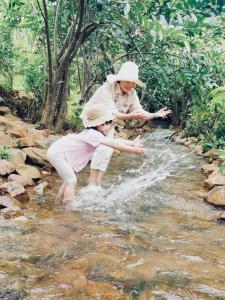 a woman and a child playing in a stream of water at HomeTa Homestay in Bao Loc