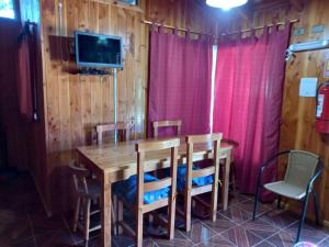 a wooden table with chairs and a tv on a wall at Lican Ray Cabañas Los Primos in Licán Ray