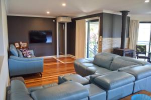 a living room with a blue couch and a tv at Jaspa - River Views - Bring your own linen in South West Rocks
