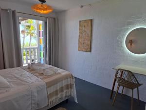 a bedroom with a bed and a table and a window at Aquavit pousada e comedoria in Jacumã