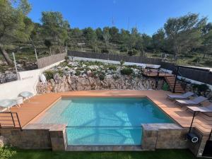 una piscina con terraza y pared de roca en Villa Vicente, en Canyelles