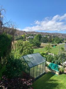 a glass house in the middle of a garden at Clock view Apartment in Alexandra