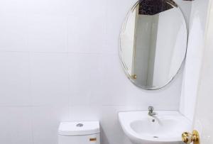 a white bathroom with a mirror and a sink at RedDoorz @ Villa E Mansion in Vigan