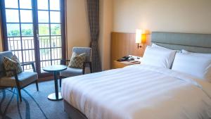 Lotte Arai Resort في ميوكو: غرفة فندق مع سرير وكرسيين