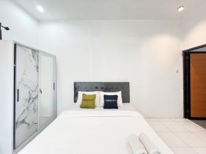a white bedroom with a bed with two pillows at Urbanview Trunojoyo Homestay Banyuwangi by RedDoorz in Banyuwangi