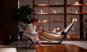 a woman sitting in a hammock with a man sleeping at Oiso Prince Hotel in Oiso