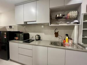 a kitchen with white cabinets and a sink at Studio at dMillenia Residences in Kota Samarahan