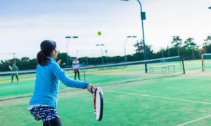 a group of people playing tennis on a tennis court at Oiso Prince Hotel in Oiso