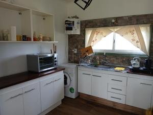 a kitchen with white cabinets and a sink and a window at Casa de campo in Mar del Plata
