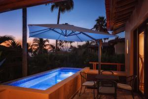 a swimming pool with a table and an umbrella at Jaguar. Beach Facing House (10 steps) - Bucerías in Bucerías