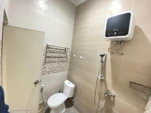 a bathroom with a toilet and a tv on the wall at Villa Lisha Orolas in Blimbing +30 photos