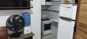 a kitchen with a white refrigerator and a fan at Kitnet para Hospedagem in Caruaru