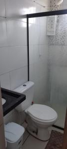 a white bathroom with a toilet and a shower at Kitnet para Hospedagem in Caruaru