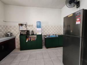 a kitchen with green cabinets and a stainless steel refrigerator at Homestay Shah Alam OneB, 2-12 pax, I-city & UiTM in Shah Alam