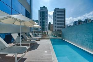 a swimming pool with chairs and an umbrella on a building at Holiday Inn Belo Horizonte Savassi by IHG in Belo Horizonte