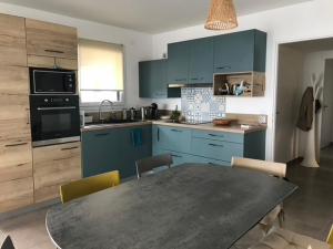 a kitchen with blue cabinets and a table with chairs at Confortable appartement 1 chambre près plage et lac avec garage - FR-1-498-111 in Publier