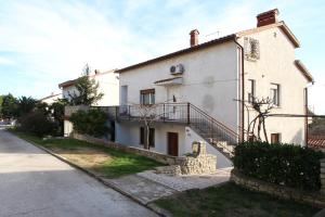 a white house with a balcony on a street at Apartment Ruža 2021 in Premantura