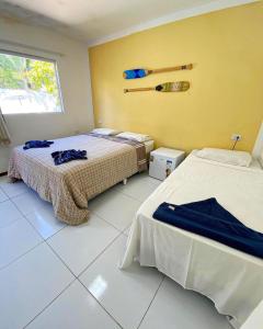 a bedroom with two beds and a yellow wall at iapôi Beira-Mar Maracaípe in Porto De Galinhas
