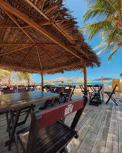 a picnic table with a straw umbrella on the beach at iapôi Beira-Mar Maracaípe in Porto De Galinhas