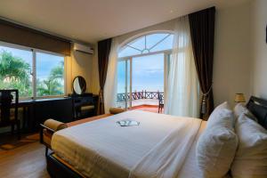 a bedroom with a large bed with a large window at Le Aqua Resort & Spa Phan Thiet - Swiss Village Resort & Spa in Mui Ne +142 photos