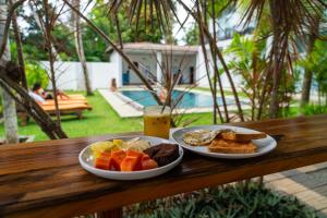 a breakfast of bread and toast and a drink on a wooden table at Green Hill Mirissa in Mirissa
