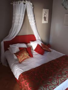 a bed with red and white sheets and red pillows at MAISON VATOSOA in Talata-maty
