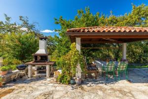 Un patio con chimenea y parrilla con sillas. en Traumhafte Finca mit Tischtennis, Spielplatz, Basketballplatz, Privatpool, Outdoor-Kueche, en Pazin