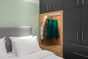 パトラにあるHOM Sleep Trip Repeatのベッドと緑のコートが入ったクローゼットのある寝室