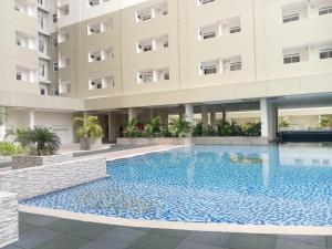 a swimming pool in front of a building at Modern Classic Studio at Loftvilles City Apartment By Travelio in Tangerang