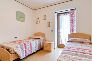 two beds in a white room with a window at Appartamenti al Parco in Molveno