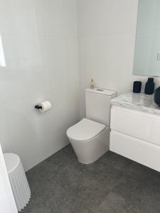 a white bathroom with a toilet and a sink at Dreamy Staiz - Riverland Abode in Barmera