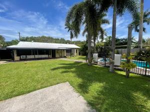a house with a pool and a yard with palm trees at Tropical family beach house in Holloways Beach